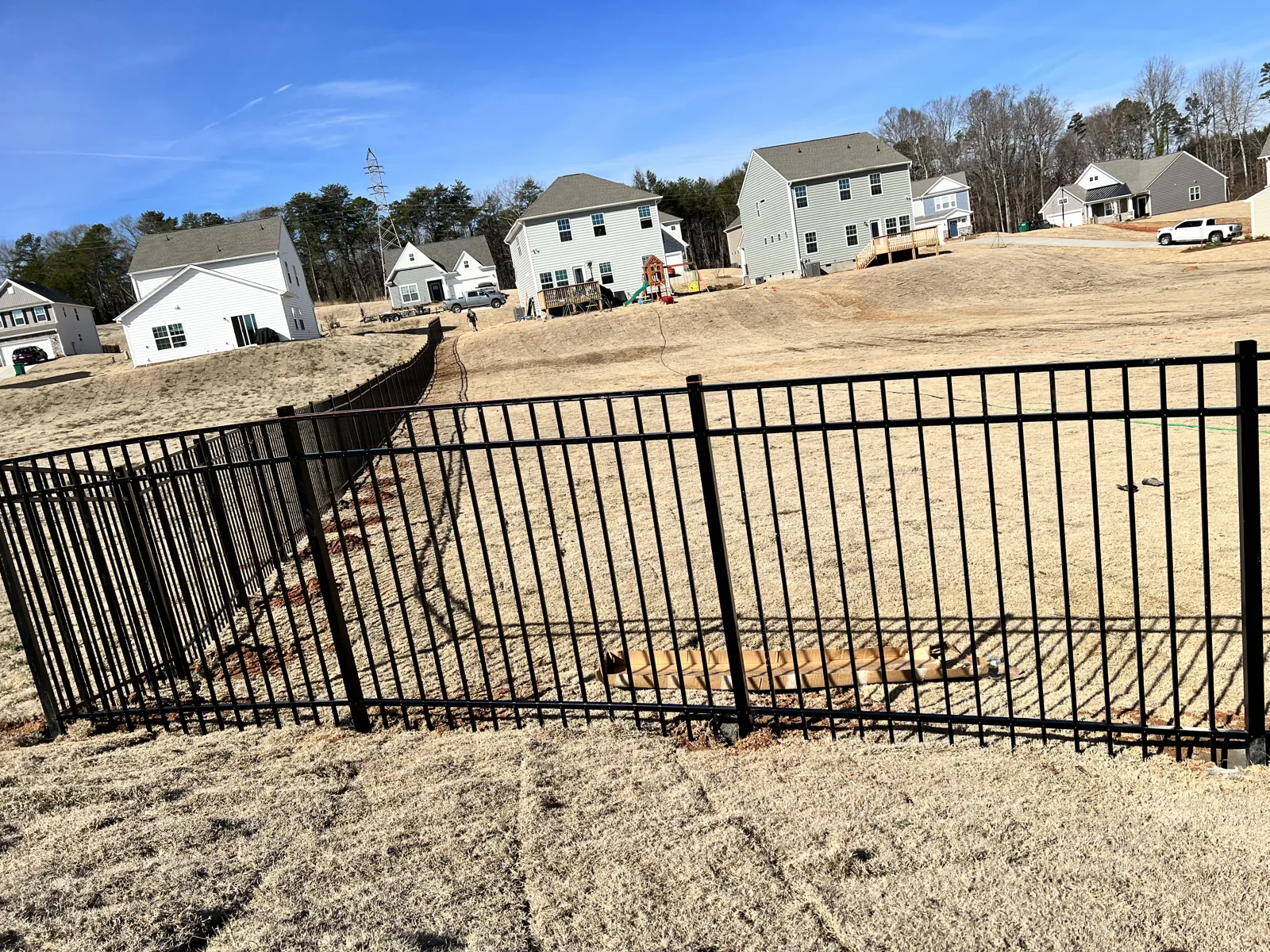 Black aluminum fence along a new-construction yard, installed by CC Fencing