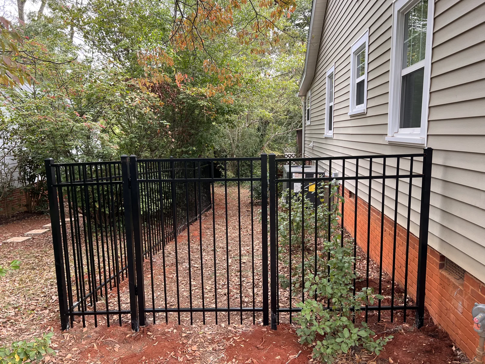 Black aluminum picket fence and gate beside a home, installed by CC Fencing