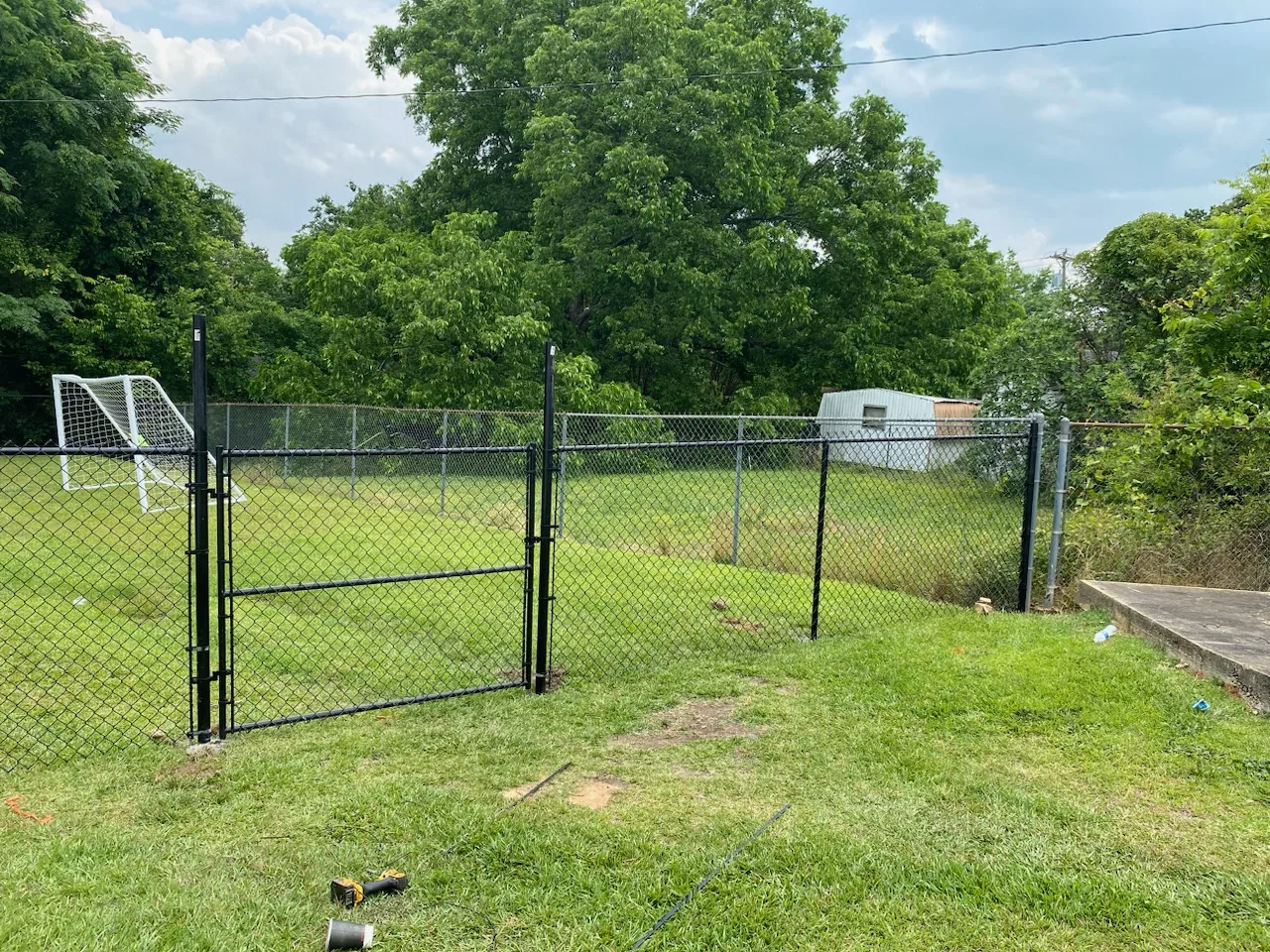 Black chain link fence with a gate in a backyard, installed by CC Fencing