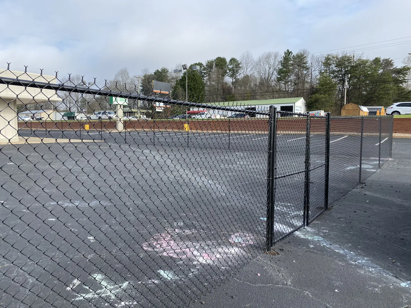 Black chain link fence enclosing a paved lot, installed by CC Fencing