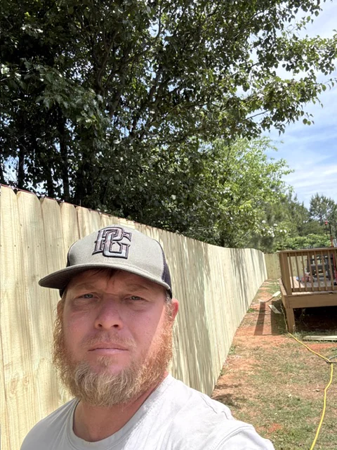 Chris Robinson, owner of CC Fencing, standing in front of a wood privacy fence his crew installed
