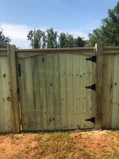Custom wood gate with an arched top and decorative hardware